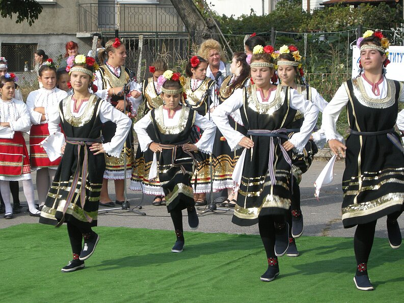 Junge Mädchen beim traditionellen bulgarischen Volkstanz Junge Mädchen präsentieren traditionellen bulgarischen Volkstanz in festlicher Nationaltracht